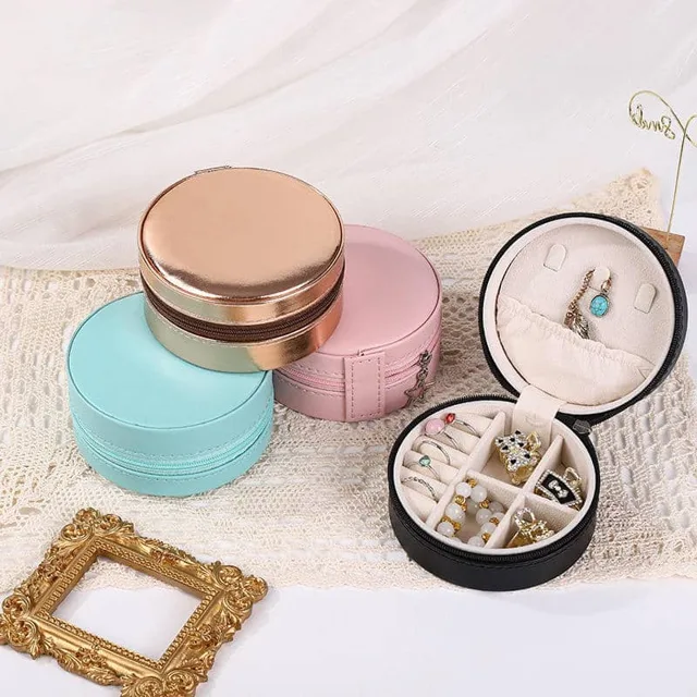 Four round travel cases in cream, gold, pink and black on a set
