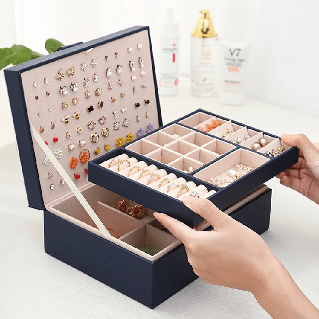 Hands opening the navy case to the earring panel and divided tray