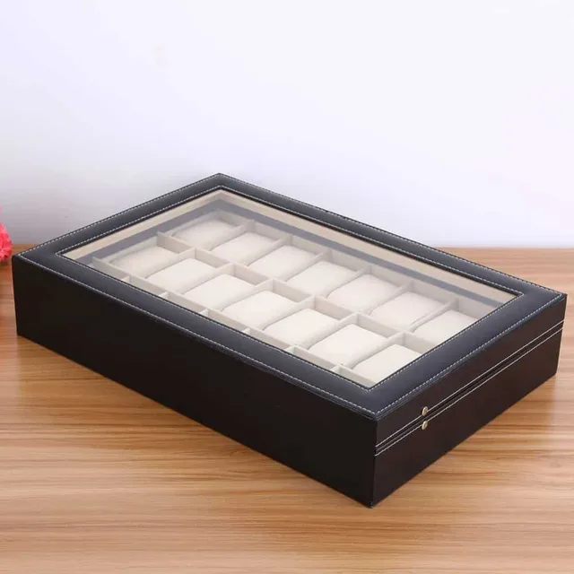 Closed black watch box with glass lid on a wooden table