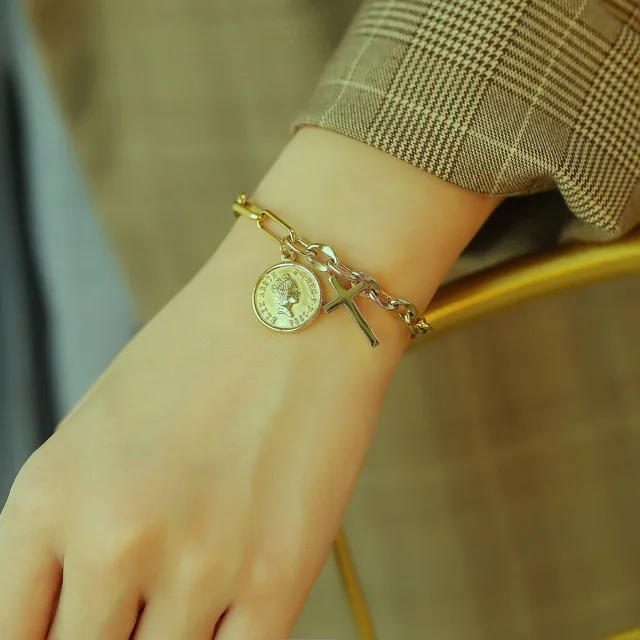 Wrist wearing the coin and cross bracelet, close view