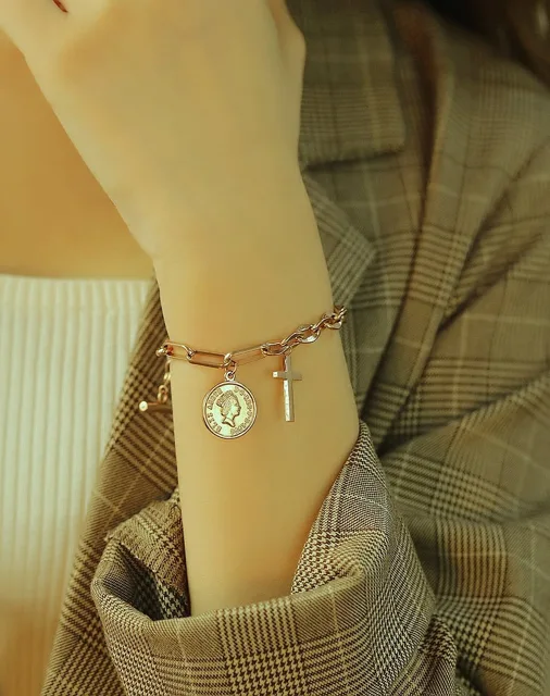 Wrist wearing the gold coin and cross charm bracelet