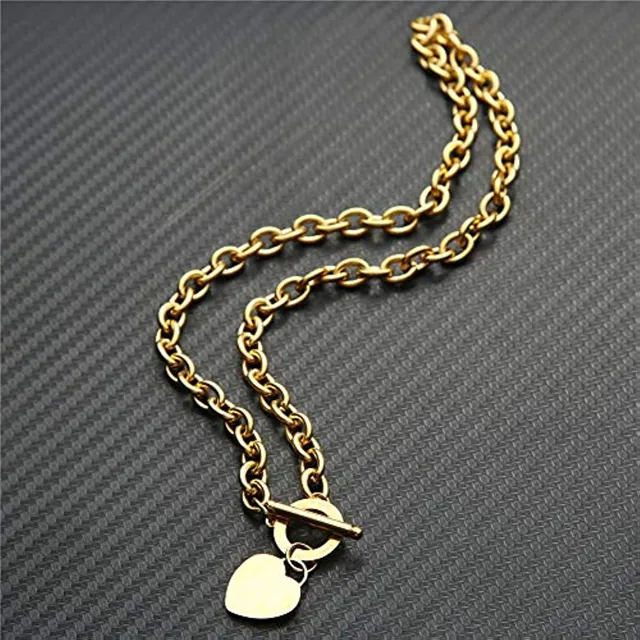 Gold heart pendant chain coiled on a dark surface