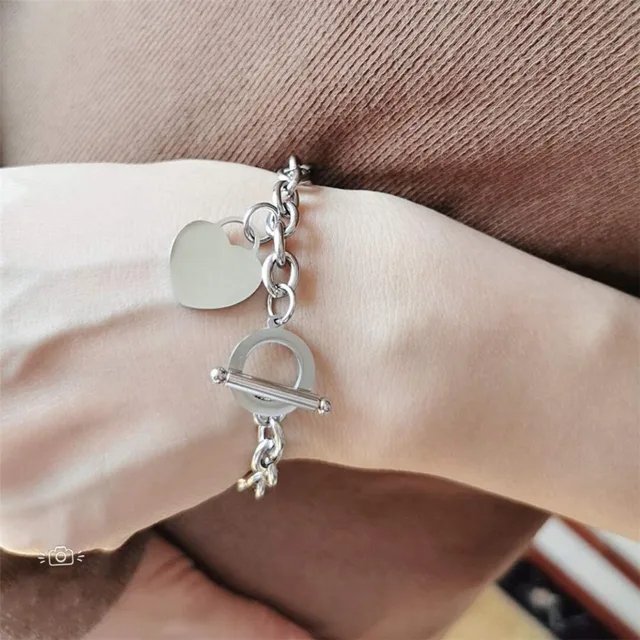 Wrist wearing a silver heart bracelet with a key charm