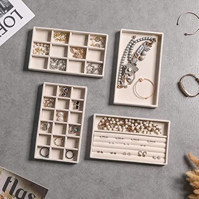 White velvet trays styled with jewelry on a marble surface