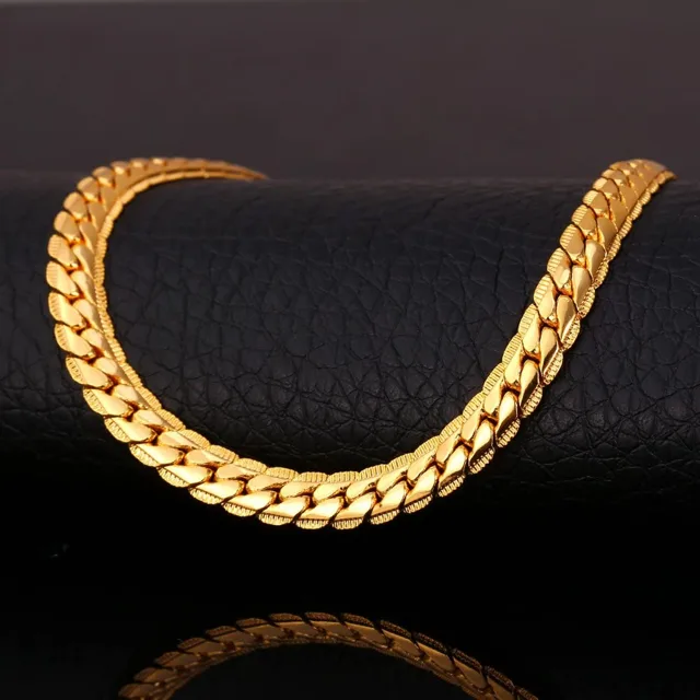 Close view of a gold Cuban link chain on a dark background