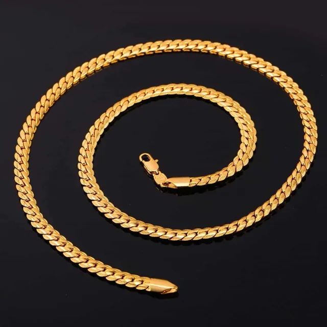 Gold Cuban link chain coiled on a dark background