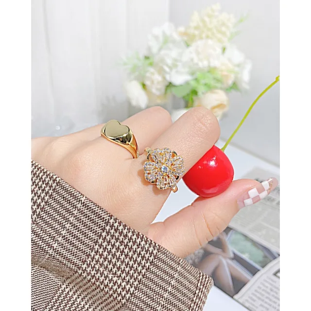 Hand wearing the gold heart ring beside cherries