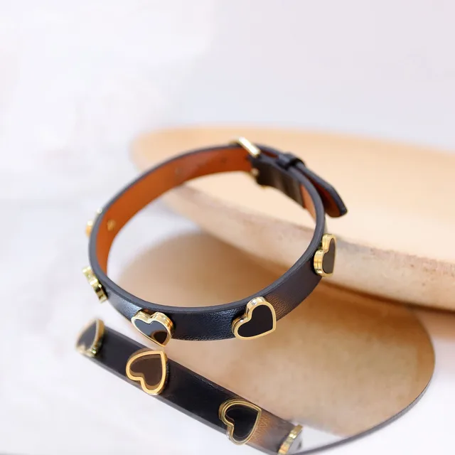Black heart-stud leather bracelet on a wooden tray