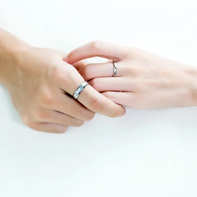 Two hands interlocked wearing the wedding bands