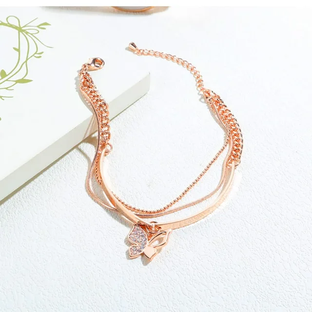 Rose gold butterfly bracelet laid beside dried flowers