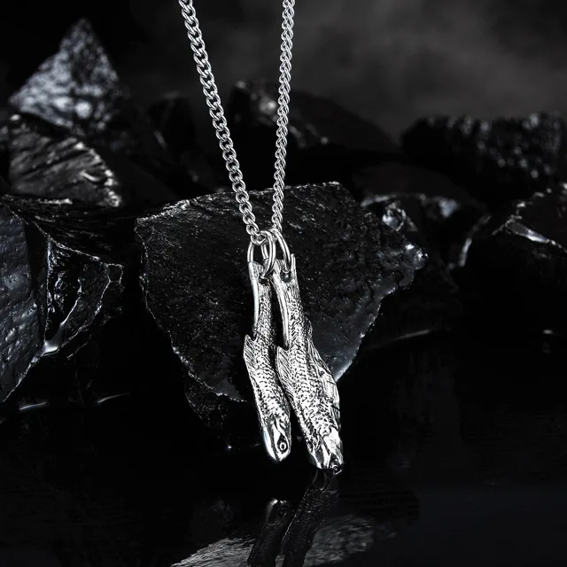 Fish pendant photographed on dark rocks
