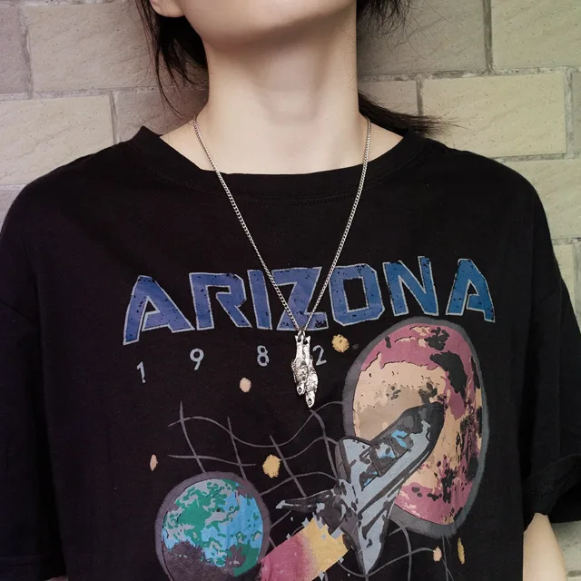 Model in a graphic tee wearing the fish pendant