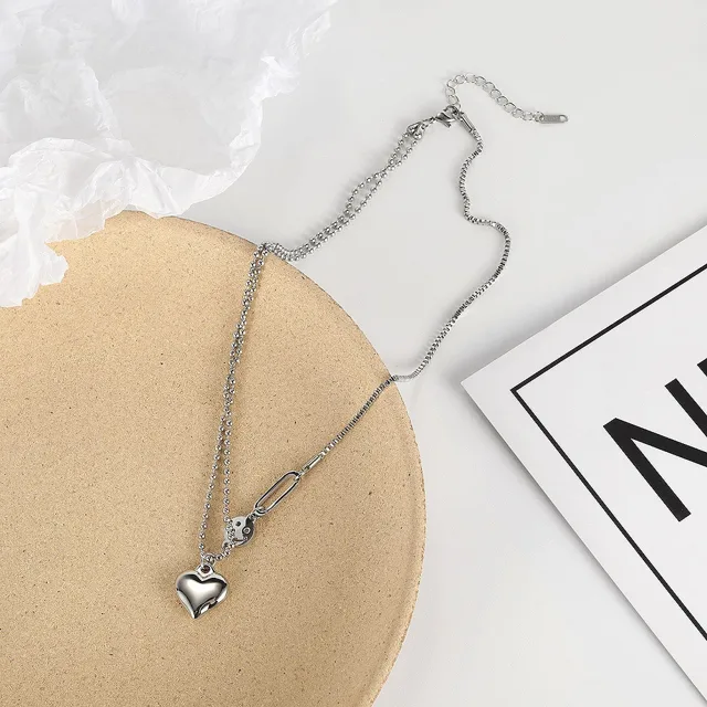 Silver heart necklace laid on linen and a beige mat