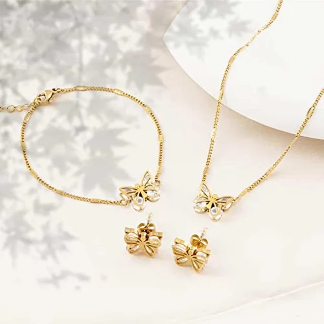 Gold butterfly bracelet and necklace on white flowers