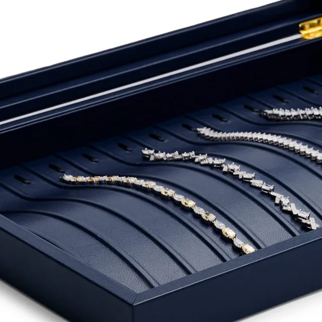 Close view of chain slots holding necklaces in a navy display case