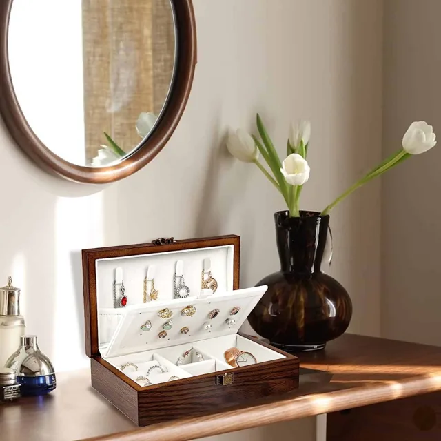 Wooden box styled open beside a round mirror and flowers