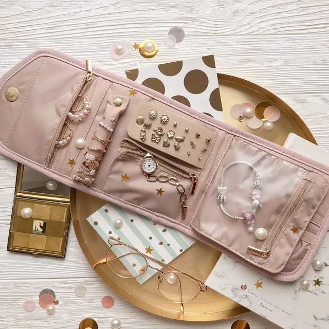 Pink jewelry roll open with jewelry arranged around it