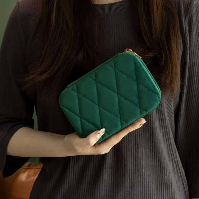 Model holding the green quilted case against a dark sweater