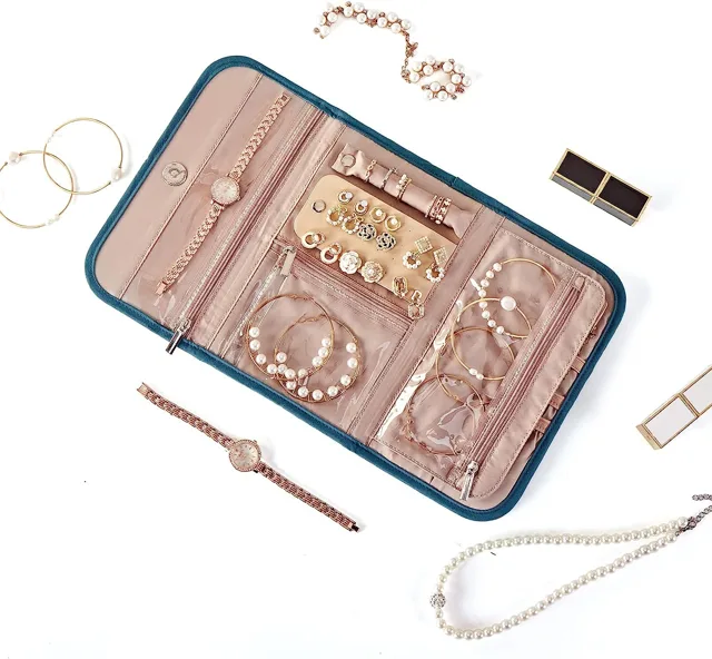 Teal jewelry roll open with loose jewelry arranged around it