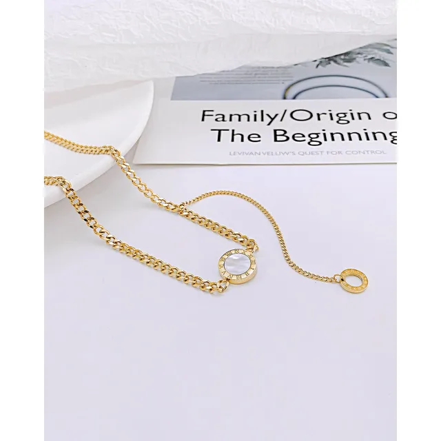 Gold clasp necklace laid on a printed card