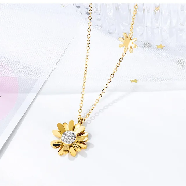 Rose gold daisy necklace laid on white linen