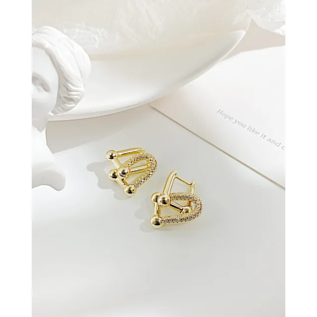 Gold earrings on white linen, close view
