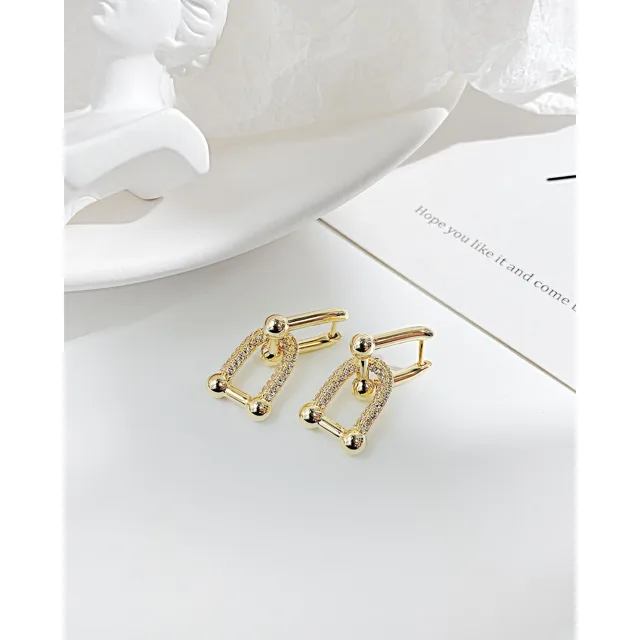 Gold geometric earrings laid on white linen