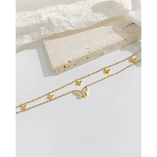 Gold butterfly anklet laid on stone and linen