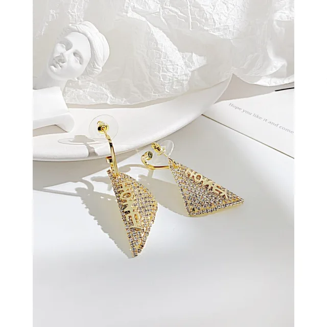Gold triangle earrings on linen, second angle