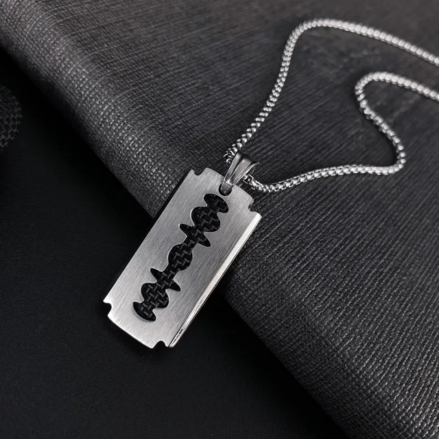 Blade pendant laid at an angle on grey fabric