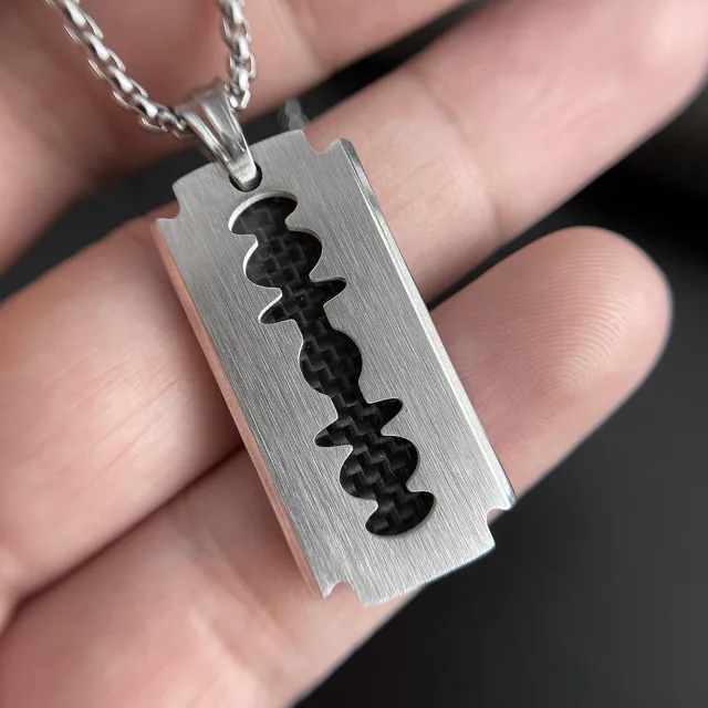 Fingers holding the razor-blade pendant