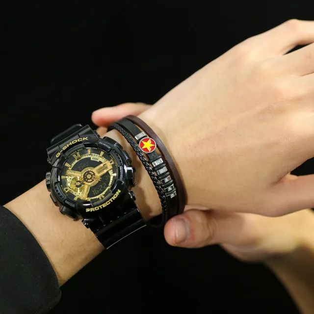 Wrist wearing the leather bracelet beside a black watch
