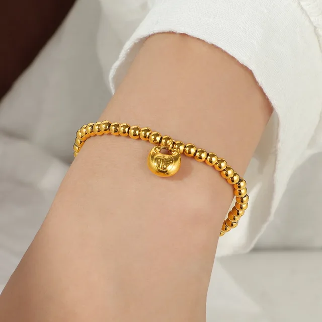 gold-tone beaded bracelet worn on the wrist, round metal beads with a stretch fit