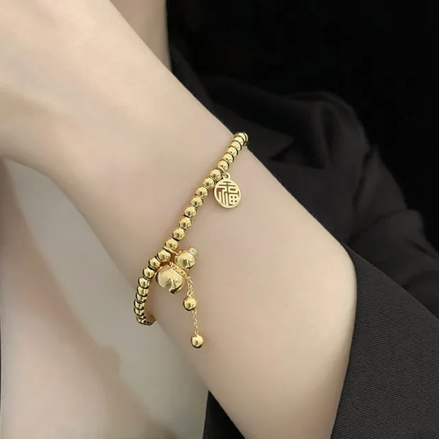 gold bead bracelet with an engraved coin charm and a small gourd pendant