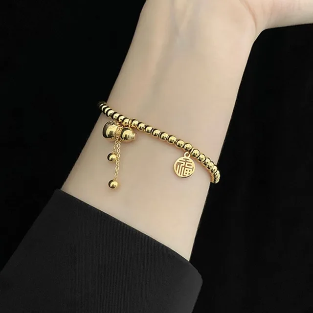 stretch bead bracelet detail showing gold-plated steel beads and the charm fitting