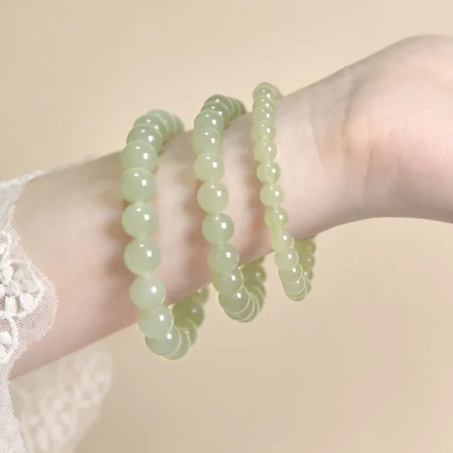 Three jade bead bracelets of graduated gauge worn together on one wrist