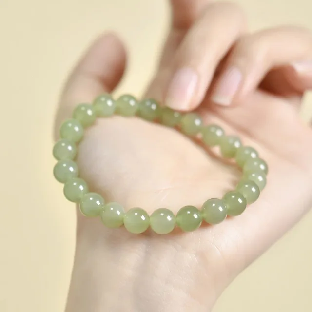 Pale off-white jade bead bracelet photographed on a hand