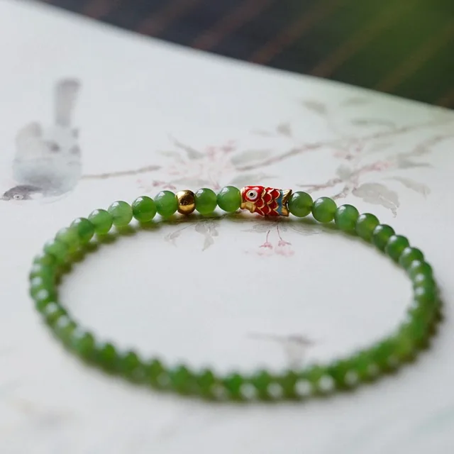 Green jade bead bracelet with a carved fish charm