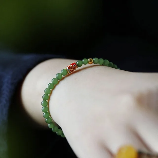 Close view of a green jade charm bracelet on a wrist