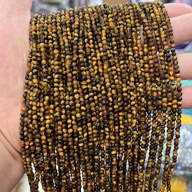 Bulk tiger's eye mini-bead strands held in a hand for beaded bracelet production
