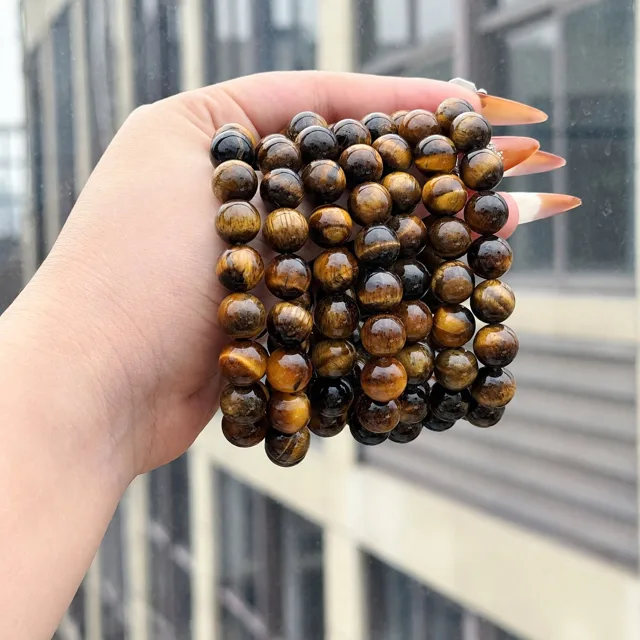 Stack of tiger's eye stretch bracelets worn over the hand with mixed gold and dark beads