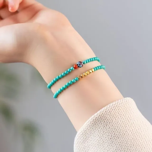 Double-layer turquoise bead bracelet worn on the wrist with small gold-tone accent beads