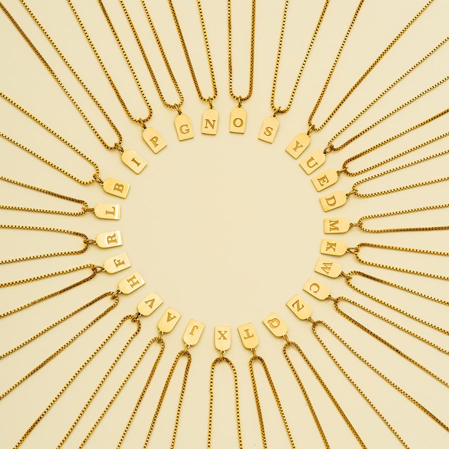 Initial letter tag necklaces in gold, full alphabet laid out