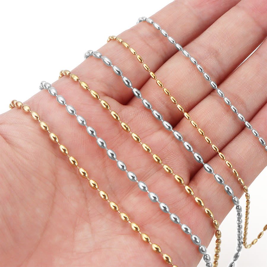 Rice bead chains in gold and steel held across a hand for scale