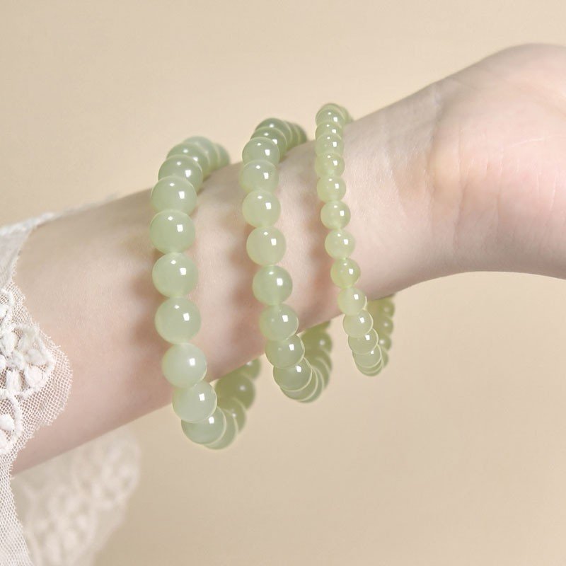 Three jade bead bracelets of graduated gauge worn together on one wrist