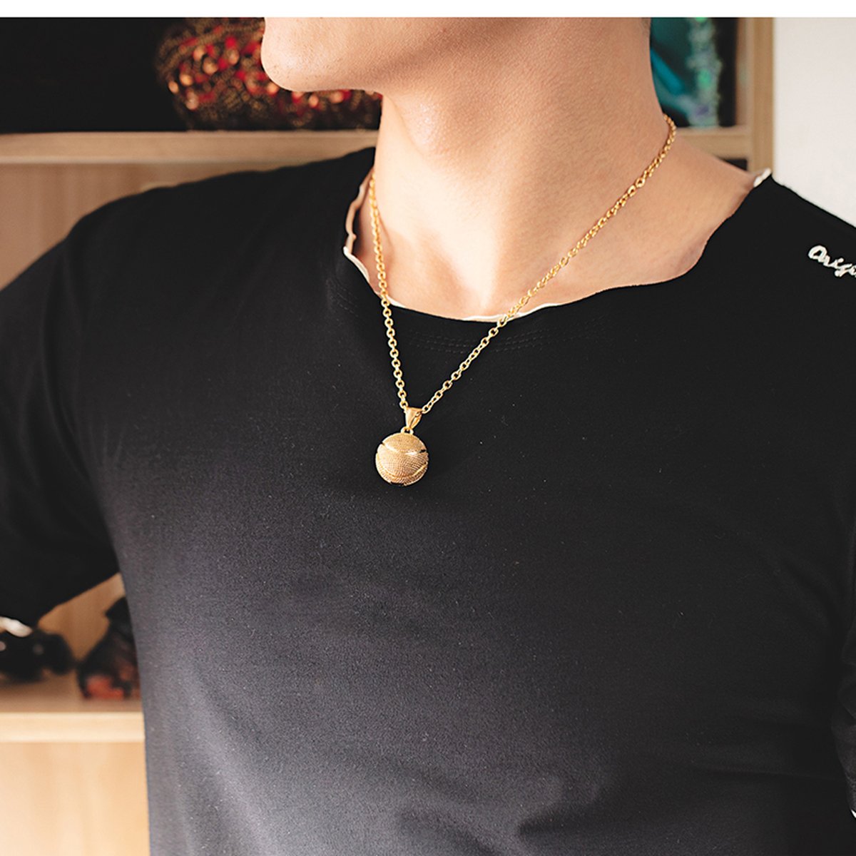 Gold basketball pendant necklace worn on a black t-shirt